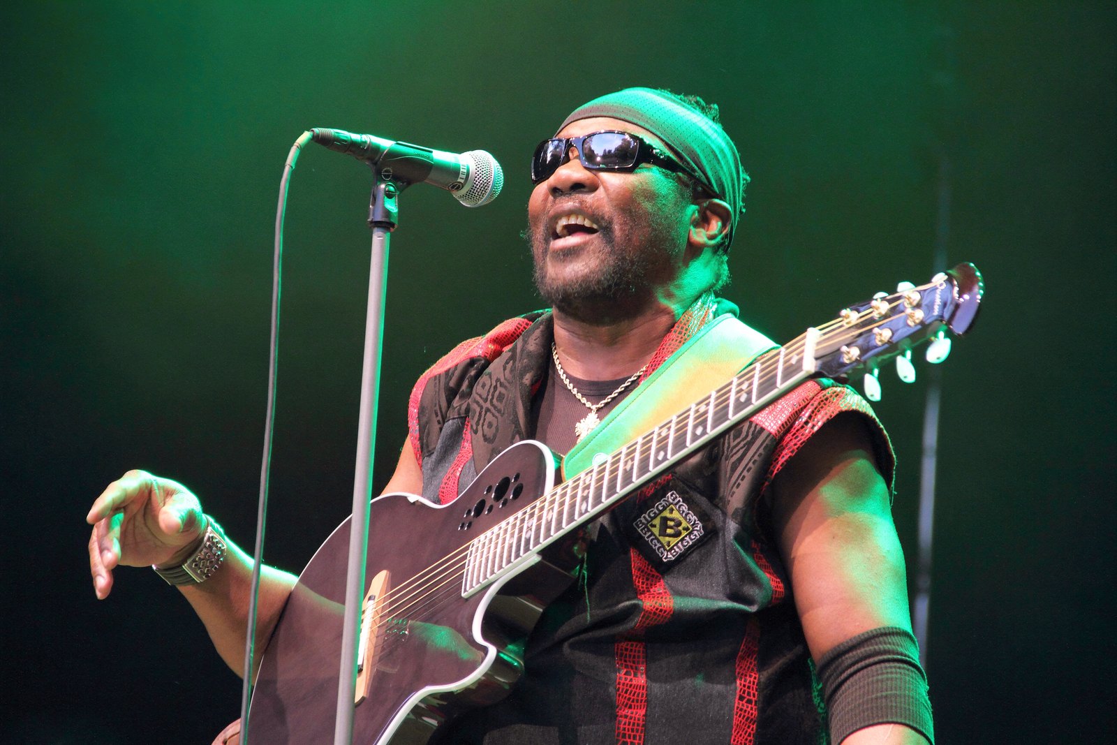 Toots Hibbert of Toots and the Maytals singing live on stage, guitar in hand